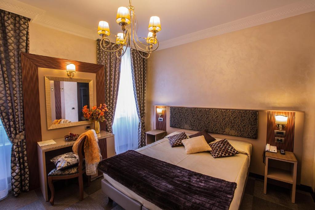 Quarto do Hotel Romano com lustre e escrivaninha